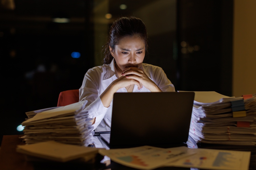 woman working late into the night, feeling stressed and burnt out, she is stuck in fight or flight mode