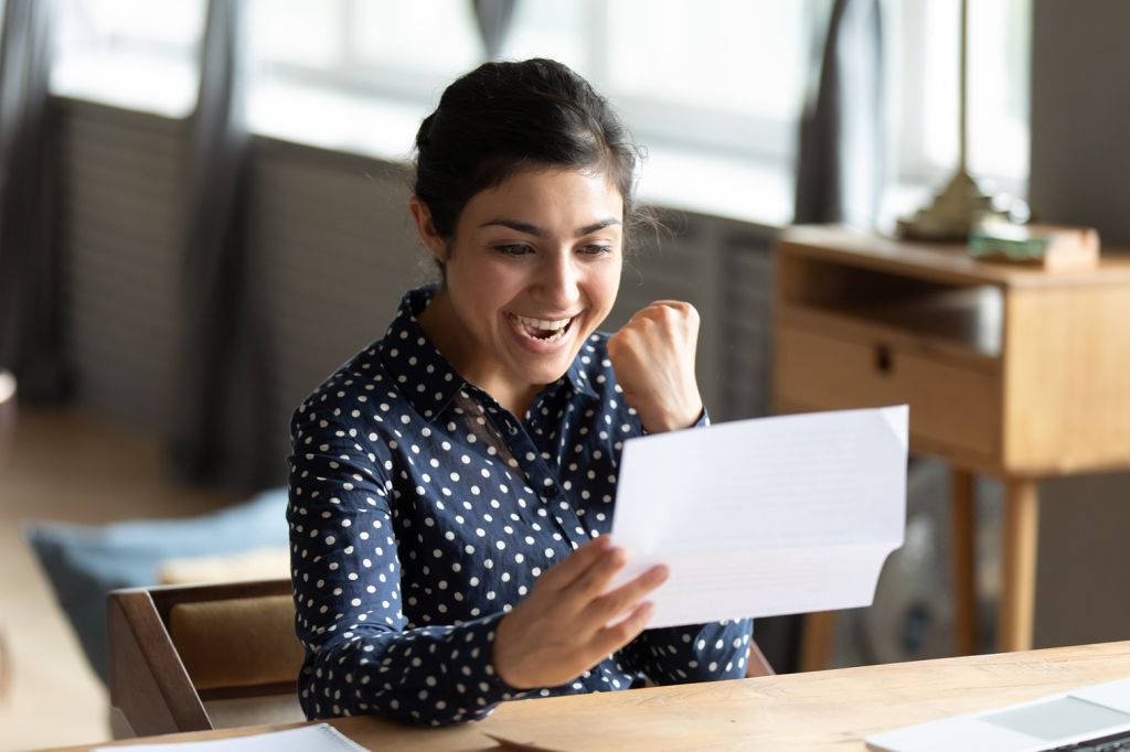 Woman looking very happily at a piece of paper after getting a pay rise