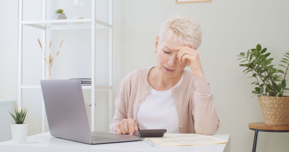 Upset senior woman with a calculator