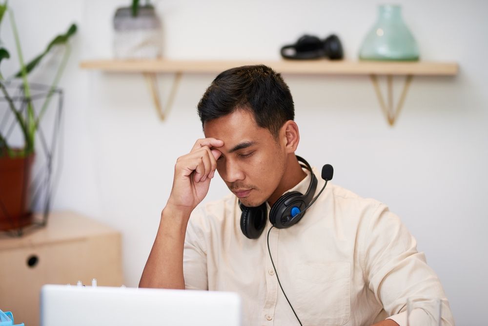 A young man looking frustrated at his computer