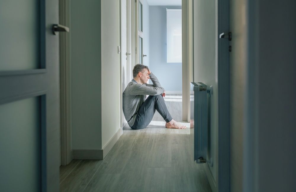 Man sitting at the end of a corridor, looking depressed or desperate