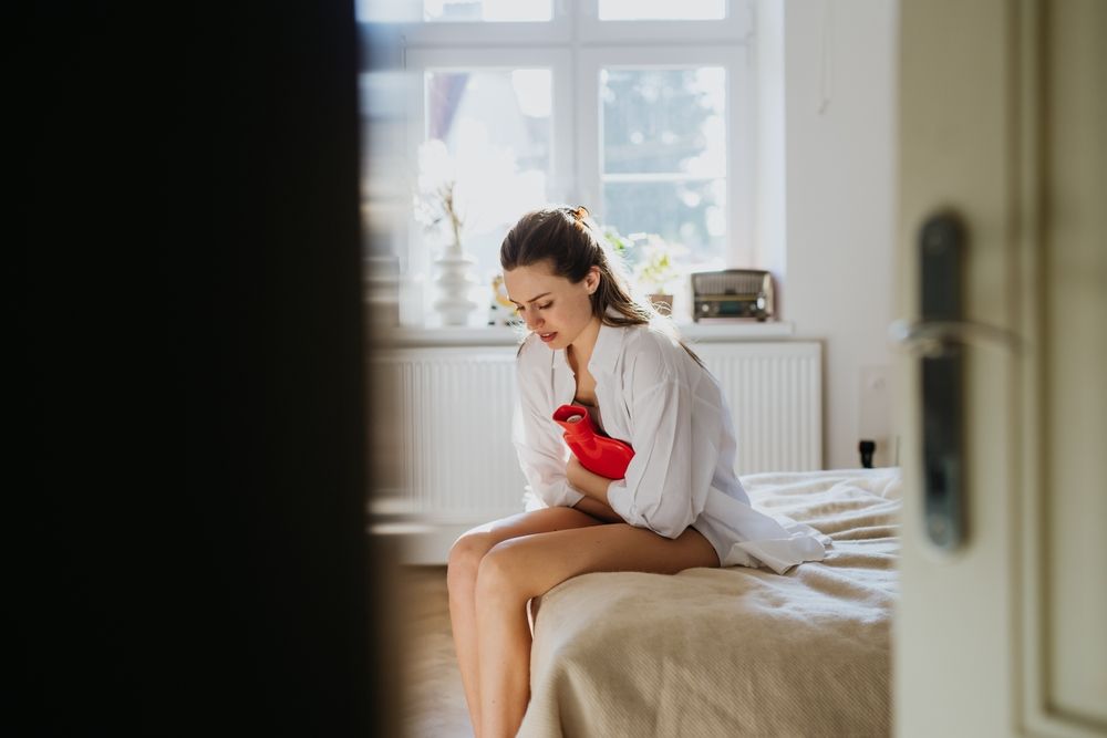 woman with a hot water bottle held to her abdomen