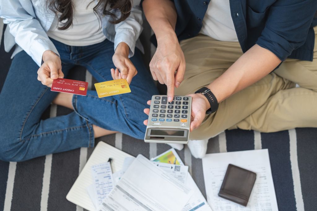 A young couple with a calculator and credit cards, trying to do their bills
