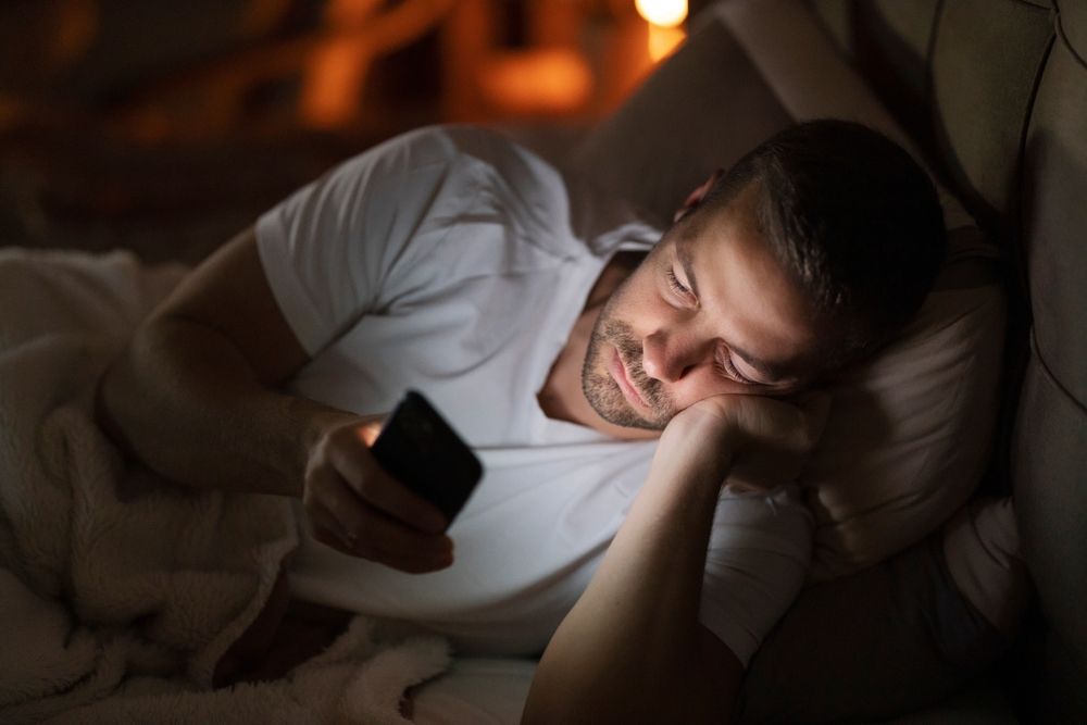 A man in bed late at night on his phone