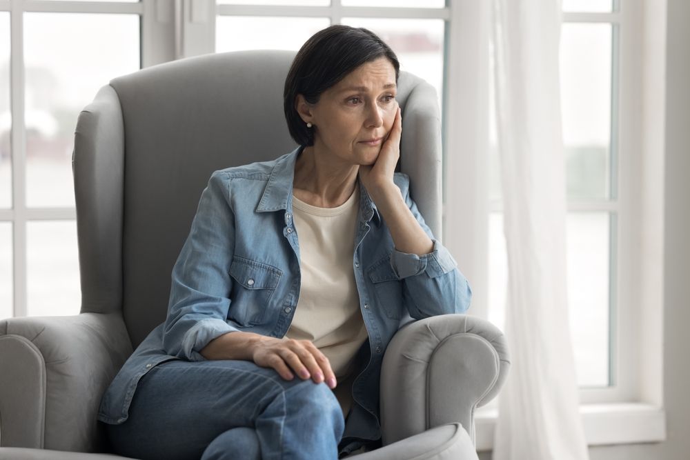 midlife woman looking upset while sitting in a chair