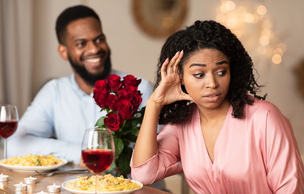 Woman looking annoyed at man with flowers