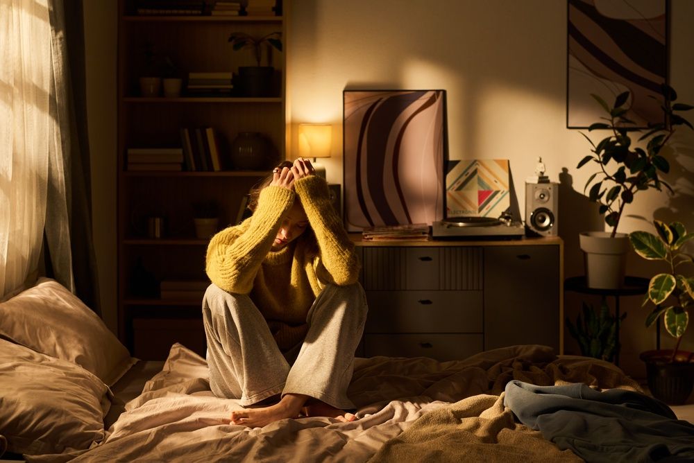 Young woman sitting in the dark looking overwhelmed and upset