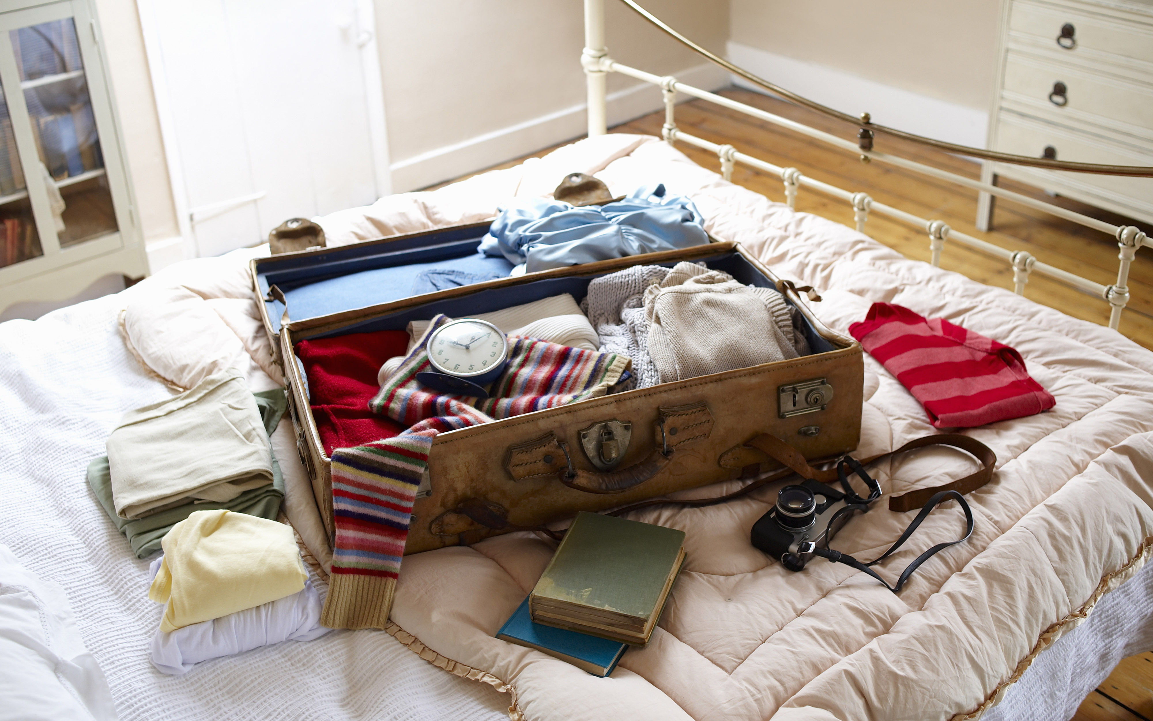 Лежат ненужные вещи. Вещи в путешествие. Чемодан с вещами. Собранные чемоданы с вещами. Вещи на кровати.